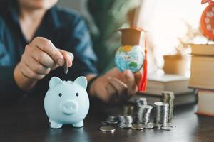 Hand putting coins in a piggy bank. Concept of saving money for a scholarship to study abroad at a university level. Financial planning accounting ideas for future education. photo