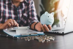 Businesswoman hand holding blue piggy bank with calculating expenses, saving money wealth and financial concept, finance, investment, Financial planning. Financial planning deposit for retirement. photo