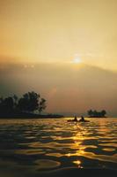 siluetas de personas en kayac a puesta de sol. foto