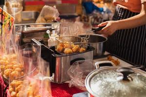 Female chef deep fried meat ball in kitchen. photo