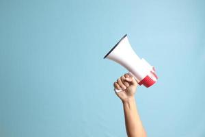 male hand holding megaphone, announcing advertisement. Isolated image on blue background photo