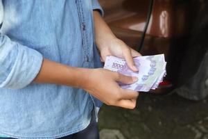 Close up of male hand holding ten thousand rupiah money banknote. Financial and savings concept photo