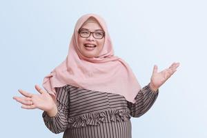 Portrait of cheerful Asian woman with hijab pulling hands towards camera, inviting someone to come inside, welcoming gesture. Isolated image on gray background photo