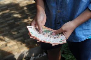 Close up of male hand holding five thousand rupiah money banknote. Financial and savings concept photo