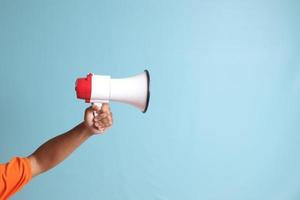 male hand holding megaphone, announcing advertisement. Isolated image on blue background photo
