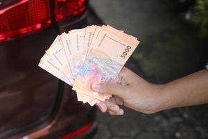 Close up of male hand holding five thousand rupiah money banknote. Financial and savings concept photo