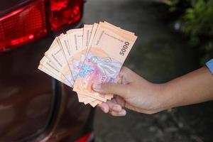 Close up of male hand holding five thousand rupiah money banknote. Financial and savings concept photo