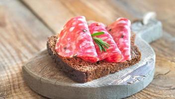 Sandwich with salami on the wooden board photo