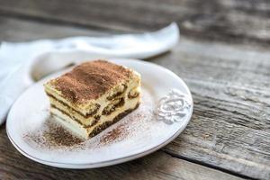 Tiramisu in the plate on the wooden background photo