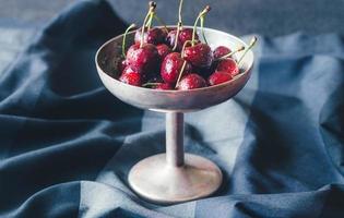 Fresh cherries in vintage silver vase photo