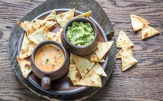 Bowls of guacamole and queso with tortilla chips photo