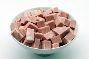 Cubes of Mortadella in a white bowl isolated on white photo