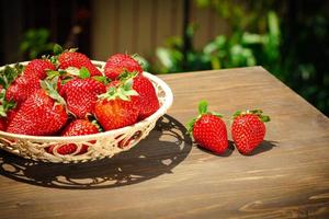 Berries of juicy strawberries in a wicker bowl in rustic style photo