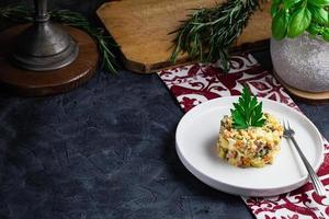 Salad with red fish, Olivier, in a white bowl on the black table photo