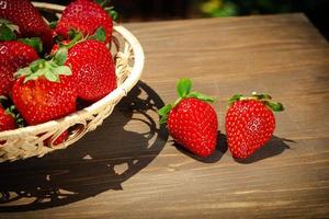 Berries of juicy strawberries in a wicker bowl in rustic style photo