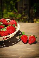 Berries of juicy strawberries in a wicker bowl in rustic style photo