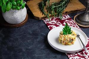 Salad with red fish, Olivier, in a white bowl on the black table photo