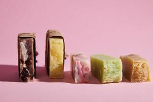 Still life with a series of organic soap bars with natural ingredients on pink isolated background. Home spa and hygiene photo