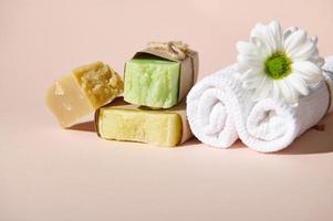 blanco toalla, manzanilla flor y apilar de orgánico jabón barras con natural ingredientes, aislado en beige. spa concepto foto