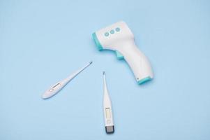 Flat lay. A set of modern infrared electronic thermometers for measuring body temperature on isolated blue background photo
