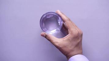 Hand halten ein Glas von Wasser gegen lila Hintergrund video
