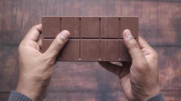 hand plocka choklad bar på trä- bakgrund video