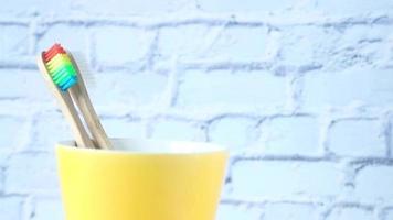 Brosses à dents colorées dans une tasse blanche contre un mur video