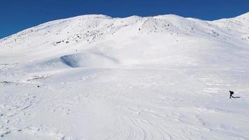 antenn Drönare se av solo- vandrare gående i de bergen under de vinter. snö vit landskap och bergsbo livsstil. video