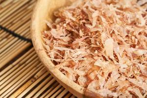 dry bonito fish flake katsuobushi in wood dish on bamboo rug table background. food dry bonito fish flake katsuobushi in wood dish on bamboo rug table background. dry bonito fish flake katsuobushi photo