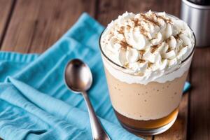 Iced coffee with whipped cream in a glass on a wooden table. photo