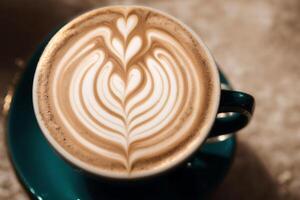 Cup of cappuccino with latte art on wooden background. photo