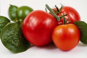 Red tomatoes with green leaves on a white background. Close-up. Healthy food concept. photo