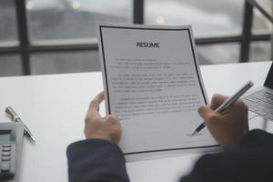 Businessman or job seeker review his resume on his desk before send to finding a new job with pen, necktie, glasses and digital tablet. photo