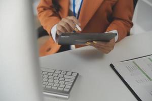 Asian Businesswoman Using laptop computer and working at office with calculator document on desk, doing planning analyzing the financial report, business plan investment, finance analysis concept. photo