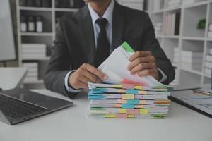 Asian Businesswoman Using laptop computer and working at office with calculator document on desk, doing planning analyzing the financial report, business plan investment, finance analysis concept. photo