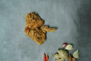 Crispy chicken wings with spices on a cement background photo