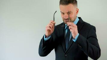 portrait de une officiellement habillé barbu homme avec des lunettes à la recherche à le caméra video