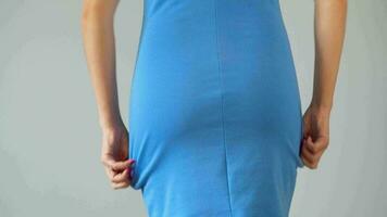 kvinna i bantning trosor bär en blå klänning på topp och checkar de resultat. begrepp av strävan för en perfekt kropp. närbild video