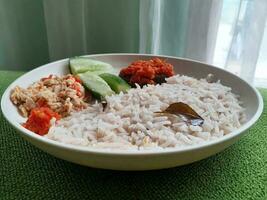 White rice and cucumber on a round white plate with a green base. photo