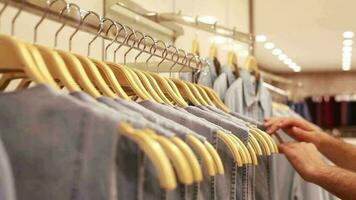 Gray colored women's dresses lined up in women clothing store, women's dresses in different sizes in store and man chosing correct size to buy, selective focus video