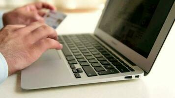 Man online shopping with credit card, man shopping on internet and entering credit card information on computer, selective focus video