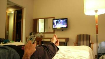 homem em repouso dentro hotel quarto e assistindo televisão, homem em repouso olhando às canais em televisão e olhando para alguma coisa para assistir, seletivo foco video