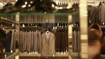 Classic clothing items on display in menswear store, leather shoes and belts sold to be used with suit in menswear store, selective focus video