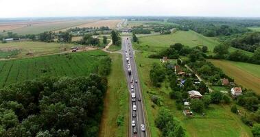 Drone shot of stuck traffic and advancing vehicles on highway, vehicles moving through scenic highway passing through green nature, time-lapse video