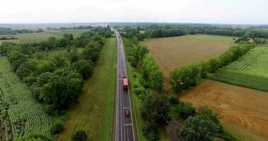 Aerial view of highway with vehicle traffic, green trees and vehicles moving on double lane road in green nature, selective focus video