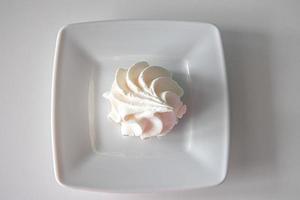 pequeño blanco sabroso dulce merengue en un blanco plato foto