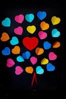colorful cut out paper hearts on a black smooth background photo