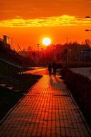 red sunset in the city with a road and walking couple of people in love photo