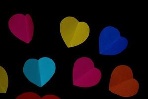 colorful cut out paper hearts on a black smooth background photo