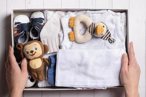 Female hands put children's clothes, shoes and toys into a box. Second hand, clothing recycling concept photo